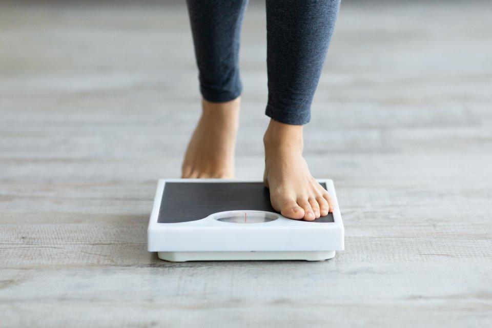 Person measuring their weight on the scale